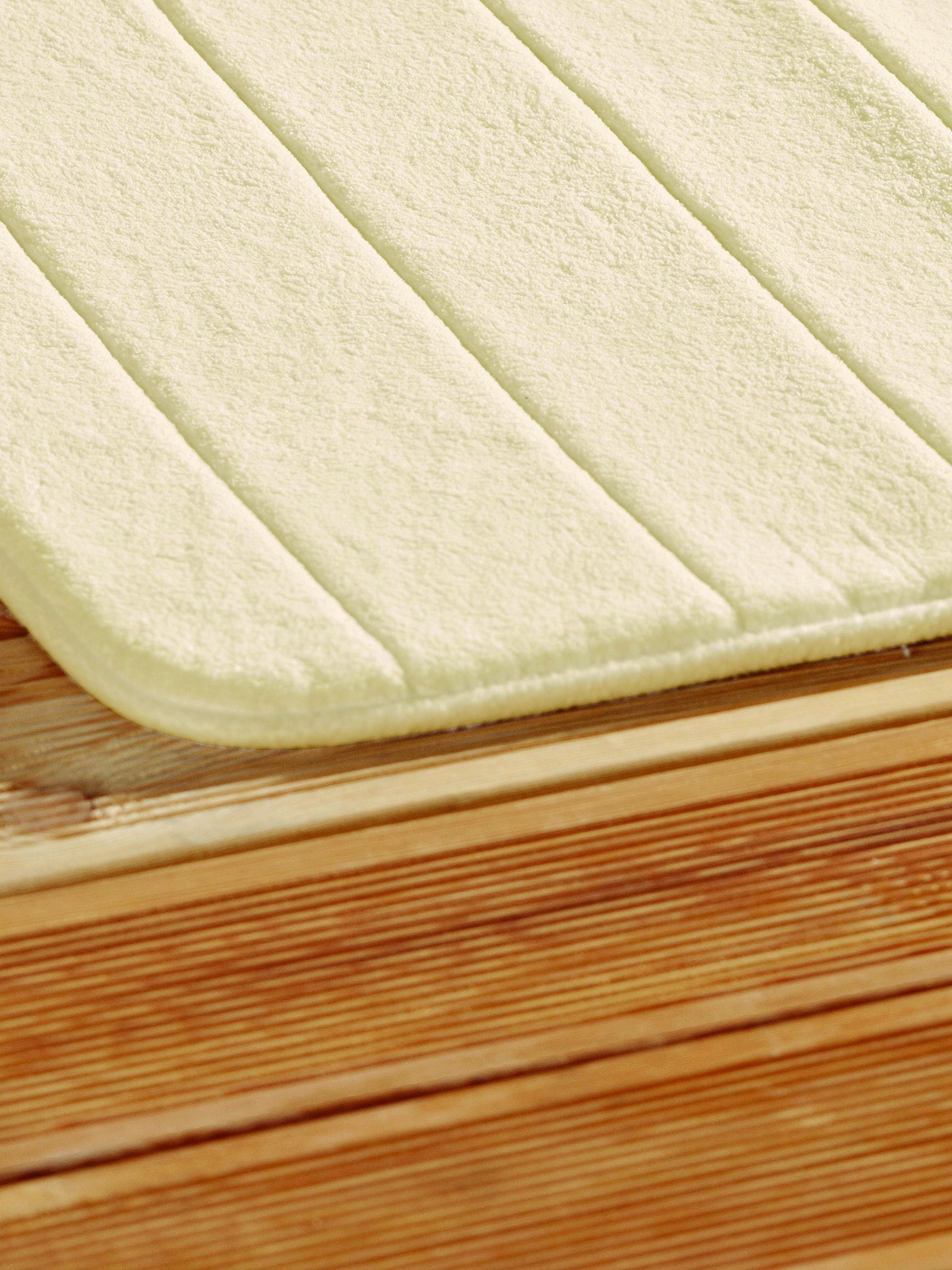 A cream ribbed bath mat on wooden boards