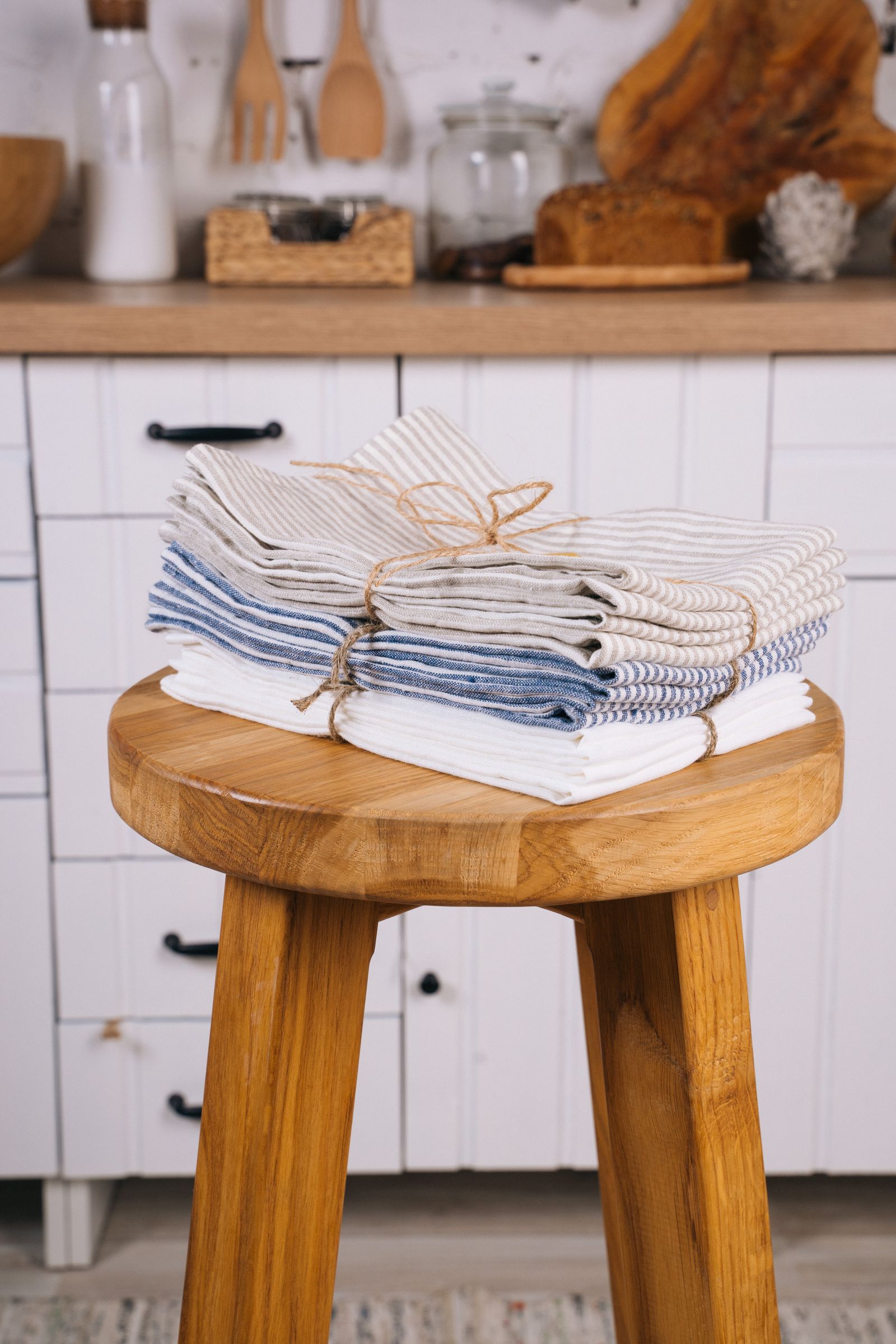 Folded striped kitchen towels stacked on a wooden stool