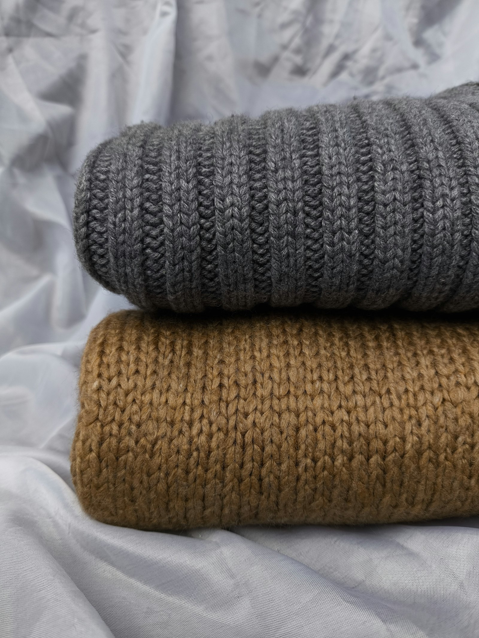 Two rolled knitted throws, charcoal and camel